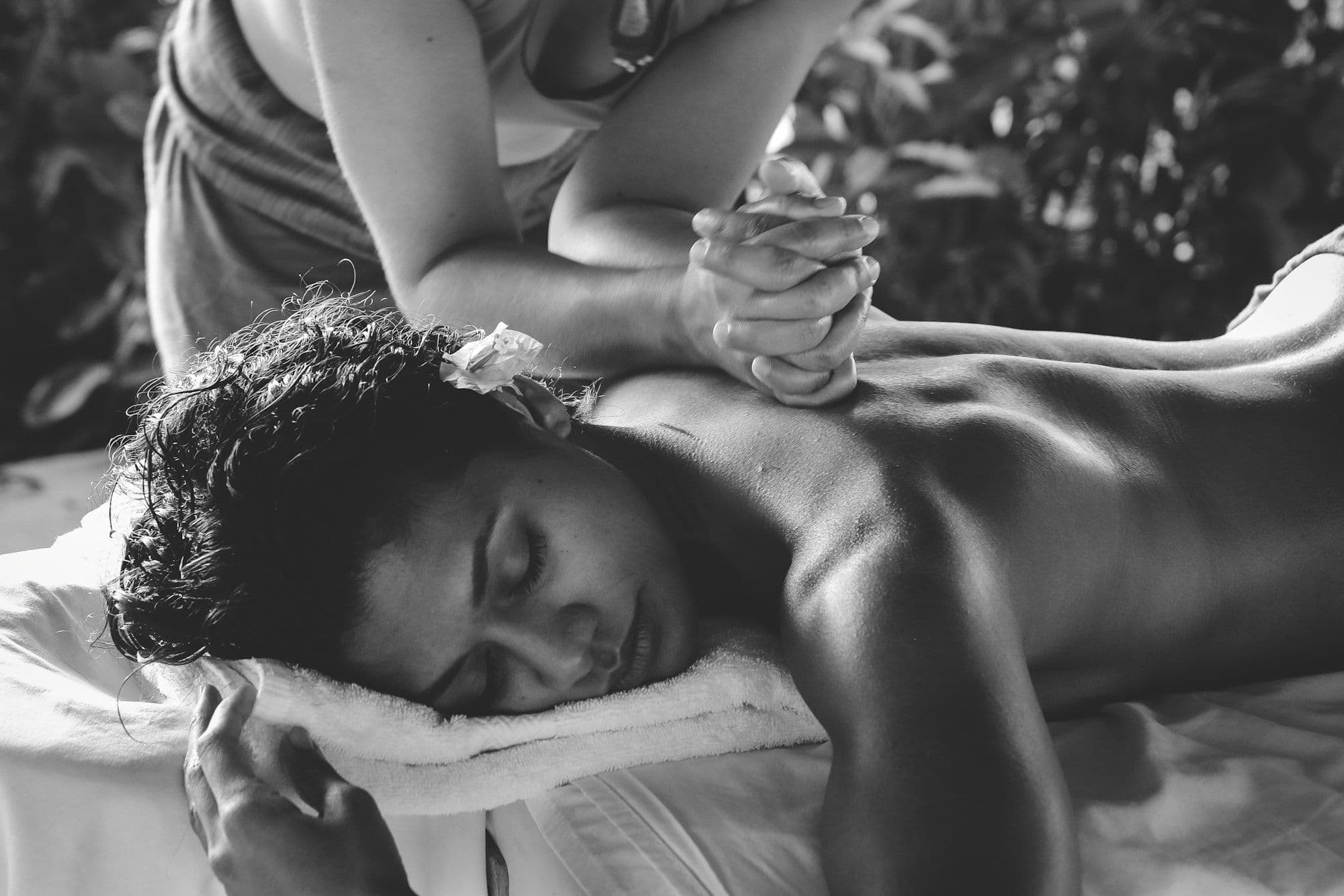 A therapist gives a calm back massage to a woman resting on a towel