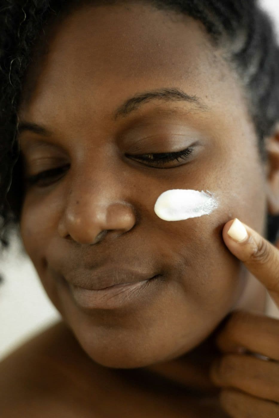 A woman smoothing cream onto her cheek